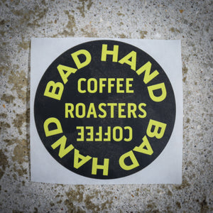 Bad Hand Coffee sticker pack, contains five waterproof stickers of various styles. Sticker two, round, with yellow text on a black background.